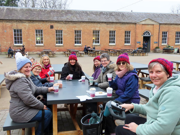 Ladies sit outside around a table with hot drinks