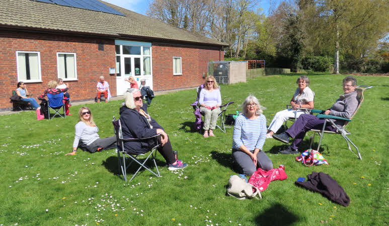 12 of our members in two large circles of six, sitting outside the Village Hall on a sunny afternoon