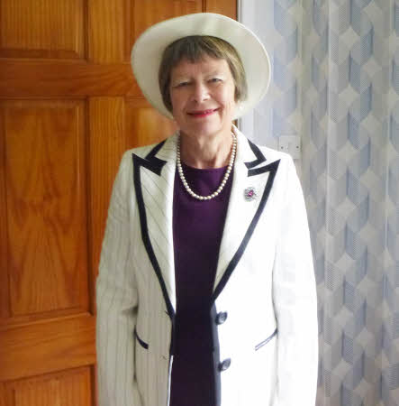 Sue dressed very smartly in a white lightly striped coat and hat with navy trim over a purple dress
