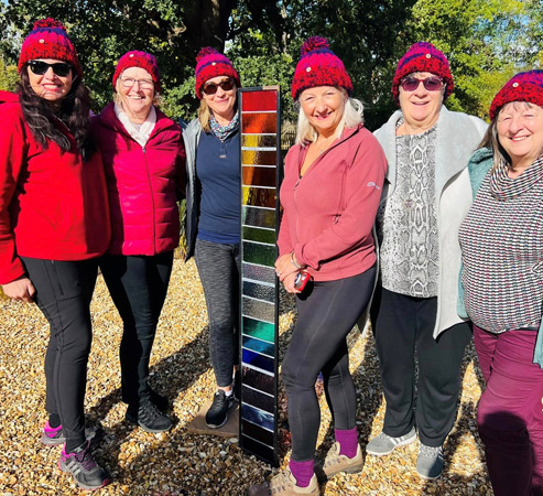 Six ladies model their bobble hats before their walk