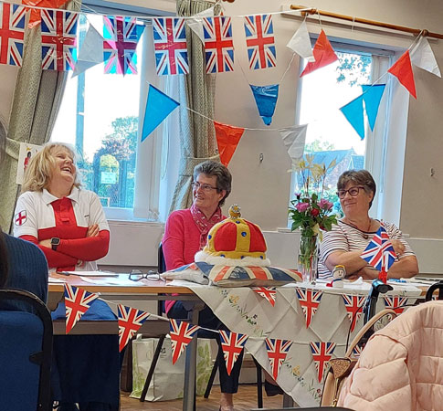 Our President and secretary look on as the treasurer laughs, all are surrounded by jubilee flags