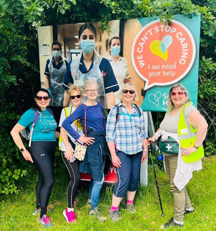 Five ladies dressed for walking pose in front of a sign for Severn Hospice