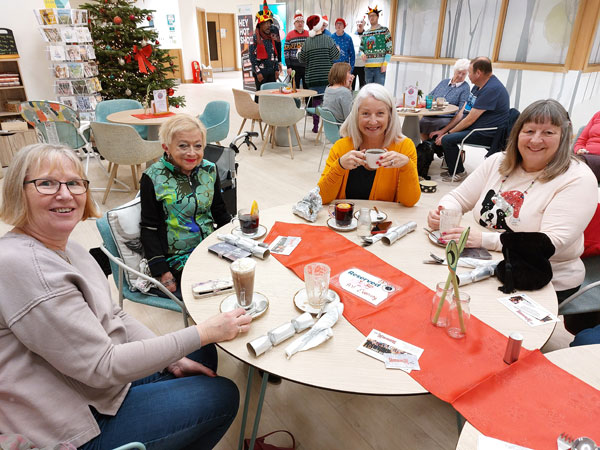 Four ladies sit in a cafe decorated for Christmas
